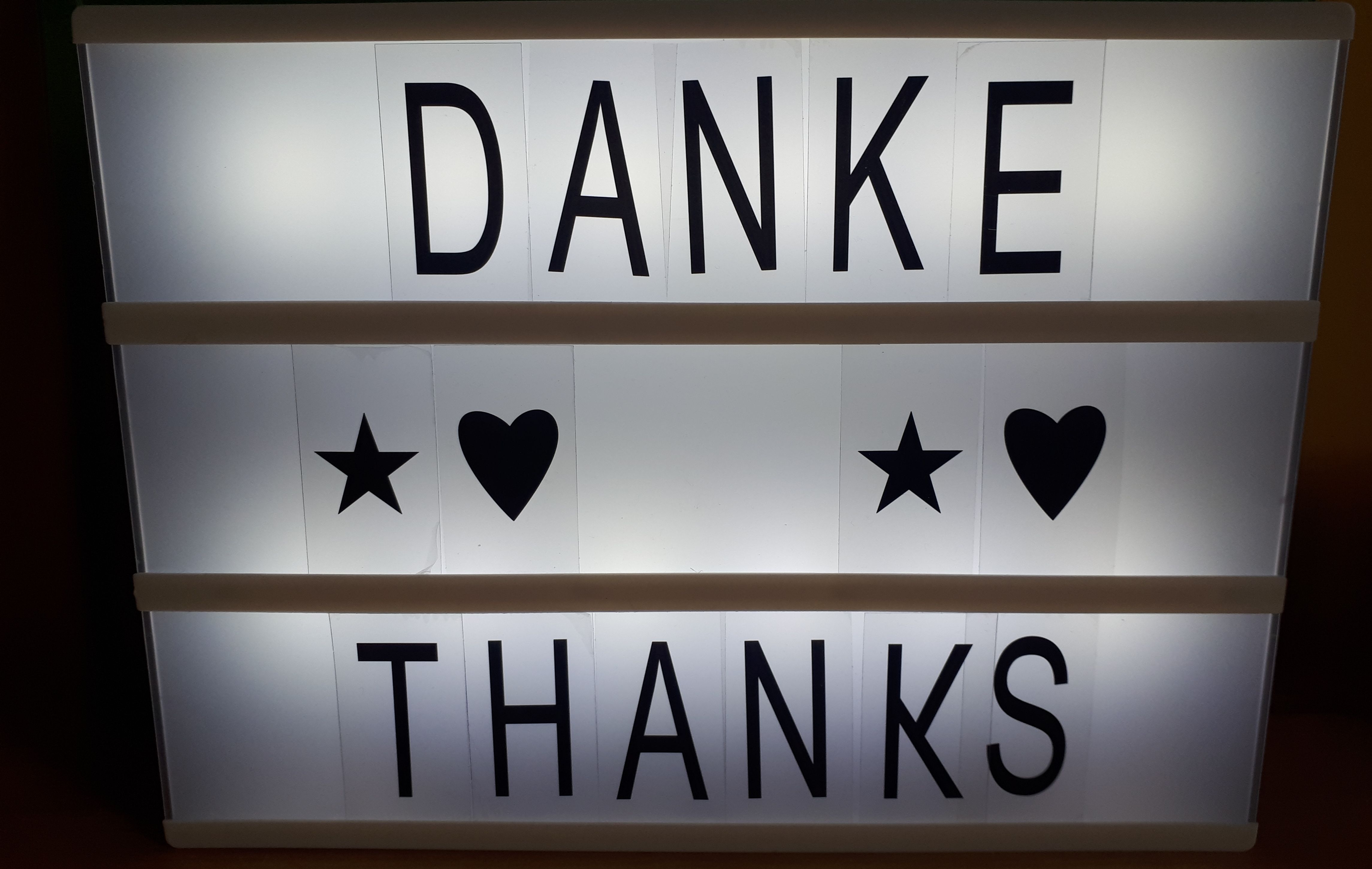 Auf einer Leuchttafel steht "Danke" und "Thanks".