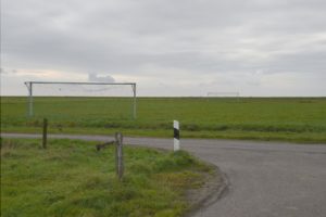 Nach einer Straßenkurve befinden sich auf dem Acker daneben zwei leere Tore mit kaputten Netzen.