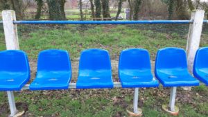 Eine leere einzelne Sitzreihe mit blauen Schalensitzen. 