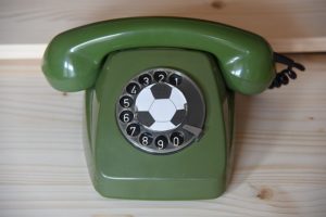 Ein grünes altes Drehwahlscheibentelefon. In der Mitte der Drehscheibe befindet sich ein Fußball.